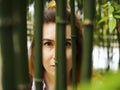 The browneyed girl looks through the green bamboo trees. Closeup photo