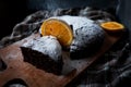 Brownie cake on a kitchen board and checkered tablecloth, decorated with oranges and powdered sugar, dark background Royalty Free Stock Photo