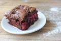 Brownie with cherries on a white plate. Close-up of chocolate cake on wooden table background Royalty Free Stock Photo