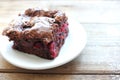 Brownie with cherries on a white plate. Close-up of chocolate cake on wooden table background