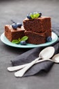 Brownie stack decorated blueberries and green mint leaves. Chocolate cake in turquoise plate on vintage black table. Homemade past Royalty Free Stock Photo