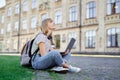 Happy student girl at university campus using laptop at summer