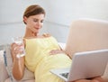 Browsing through the pregnancy blogs. a beautiful pregnant woman enjoying a glass of water while using a laptop at home. Royalty Free Stock Photo