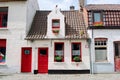 Bruges, Belgium - August 2010: Small picturesque white houses with red doors, red window frames, red flowers and red roof tiles