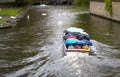 Bruges, Belgium - October 11 2019: Tourist boat goes under rain on canal with swans near Begijnhof Royalty Free Stock Photo