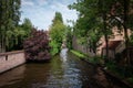 Bruges canals on a sunny day with white clouds. Picturesque landscape Swans swimming in the canal Royalty Free Stock Photo