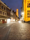 Bruges by night. Cobbled street and illuminated historical city centre with Belfort Tower, Belgium, Europe