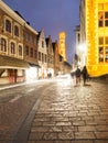 Bruges by night. Cobbled street and illuminated historical city centre with Belfort Tower, Belgium, Europe