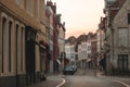 narrow street with beautiful old houses and cars at sunset, brugge, belgium Royalty Free Stock Photo