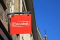 Closeup of logo lettering of dutch drugstore chain kruidvat over shop entrance against blue sky