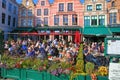 View over market square with busy cafes and restaurants, people sitting outside aggainst clear blue autumn sky