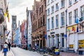 Narrow cobblestone streets and brick houses with step gables and the Belfry Tower in the background in the city of Bruges, Belgium