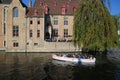 View over water canal with full tourist tour sightseeing boat on medieval house with outside restaurant terrace and green tree