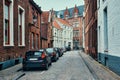 Brugge street with cobblestone road with parked cars and old medieval houses. Bruges, Belgium Royalty Free Stock Photo