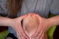 Bruise injury on young woman knee. Close up image of female person sitting on sofa and holding in hands wounded leg with