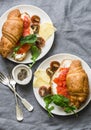 Brunch or breakfast table - croissants with cream cheese and smoked salmon, and cherry tomatoes. Delicious balanced breakfast, br