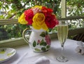 A brunch table set with bouquet of roses and flute of champagne