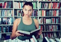 Girl surprised chooses a book in the library Royalty Free Stock Photo