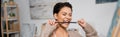 Brunette artist biting paintbrush near blurred Royalty Free Stock Photo