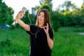 A brunette asian girl smiling talking on the phone on a video call. In the summer in park on a green meadow. Hand Royalty Free Stock Photo