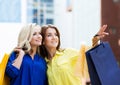 Brunette with beautiful young blond pointing with shopping bags Royalty Free Stock Photo