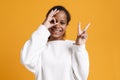 Brunette black girl smiling while showing ok and peace sign Royalty Free Stock Photo