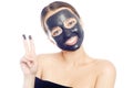 Brunette in black mask for the face. Beautiful girl with perfect skin. A young girl takes care of herself. A girl shows a gesture