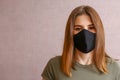 brunette in a black mask. a young woman in a cloth mask on a light background. protection against coronavirus infection, covid-19