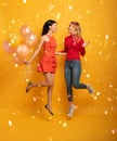 Girls ready for a party with balloons. Joyful an happiness expression. Yellow background