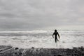 Brunette boy in the black swimsuit with a surf in his hands walking to the sea Royalty Free Stock Photo