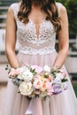 Brunette bride in a beautiful pink wedding dress with embroidery on a corset holding a bouquet of peonies Royalty Free Stock Photo