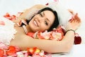 Brunette bride on the bed covered with rose leaves