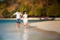 Brunette bride and groom run in shallow sea Royalty Free Stock Photo