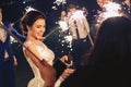 The bride and the guests hold the sparklers and amuse themselves