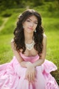 Brunette bride in pink wedding dress resting and sitting on green grass at spring park. beauty portrait. Royalty Free Stock Photo