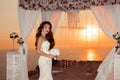 Brunette bride portrait. Wedding ceremony arch with flower arrangement and white curtain on cliff above sea at sunset, outdoor ph Royalty Free Stock Photo