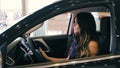 Brunette Woman in Luxury Car salon holding hands on steering wheel