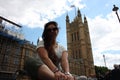 Brunette Caucasian tourist girl resting sitting under the seat of two houses of parliament in Westminster in London Royalty Free Stock Photo