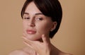 Brunette European woman performing lifting rejuvenating massage on her neck,posing against beige background with copy space. Skin Royalty Free Stock Photo