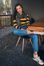 Brunette Caucasian woman sitting outdoors at comfortable cafeteria while waiting friend and her lunch. Happy young female sitting Royalty Free Stock Photo