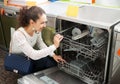 Brunette choosing new dish washing machine Royalty Free Stock Photo