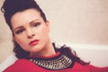 Brunette with curly hair in a red dress lies in an empty white bathtub Royalty Free Stock Photo