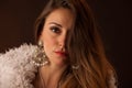 Brunette dancer posing in a white fluffy coat in front of dark background