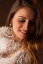 Brunette dancer posing in a white fluffy coat in front of dark background