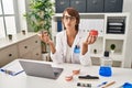 Brunette dentist woman holding apple and chocolate doughnut looking at the camera blowing a kiss being lovely and sexy Royalty Free Stock Photo