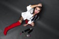 Brunette with dined hair in a white shirt and black shorts and red boots sits on a grey background and holding his head with his Royalty Free Stock Photo