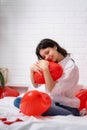 Brunette European girl rejoices on bed with red heart shape balloons. Morning love surprise gift on valentines day Royalty Free Stock Photo