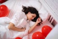 Brunette European girl sleeping on bed with red heart shape balloons.Morning surprise gift on valentines day Royalty Free Stock Photo