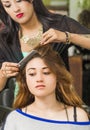 Brunette facing camera getting hair done by Royalty Free Stock Photo