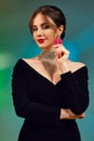 Brunette female in black dress, necklace and earrings. She is smiling, showing two red chips, posing on colorful Royalty Free Stock Photo